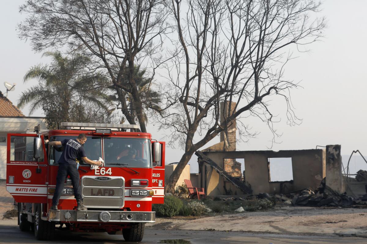 A firefighter cleans the windows on a fire truck for visibility in Bell Canyon.