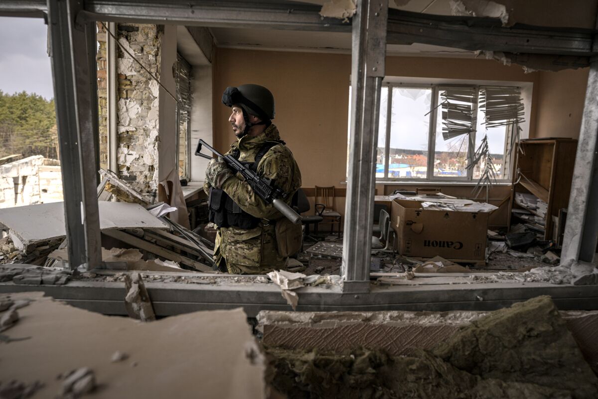 A Ukrainian serviceman stands in a heavily damaged building