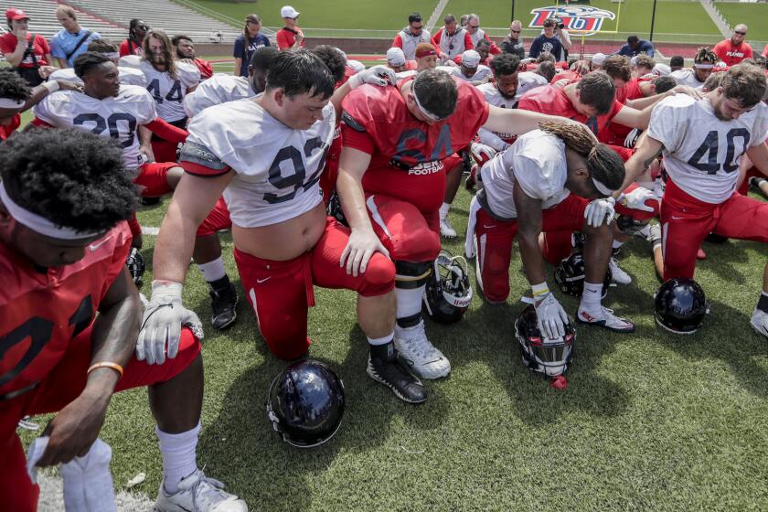LYNCHBURG, VIRGINIA, SATURDAY, AUGUST 18, 2019 - Liberty University football players kneel in prayer following an intersquad scrimmage at Williams Stadium. Defensive lineman Mason Wolk, 92, in front. Left to right are, Treon Sibley, Wolk, Jacob Bodden, Rion Davis and Zack Amerson. (Robert Gauthier/Los Angeles Times)