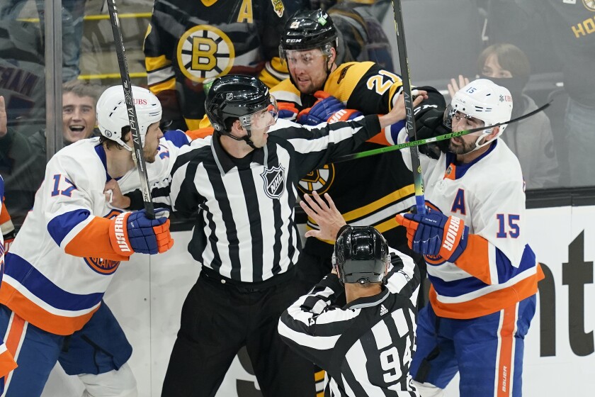 Referees keep Boston Bruins left wing Nick Ritchie (21) from fighting with New York Islanders left wing Matt Martin (17) and right wing Cal Clutterbuck (15) in the first period of Game 1 during an NHL hockey second-round playoff series, Saturday, May 29, 2021, in Boston. (AP Photo/Elise Amendola)