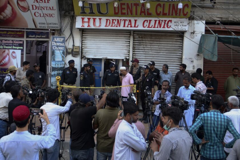 Police officers and media gather outside a dental clinic after a firing incident, in Karachi, Pakistan, Wednesday, Sept. 28, 2022. A gunman shot and killed a dual national Chinese-Pakistani man in an attack at a dental clinic in the southern port city of Karachi on Wednesday before fleeing the scene, police said. (AP Photo/Fareed Khan)