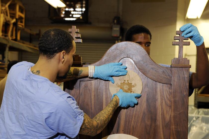 Inmates Evan Davis, left, and Rameen Perrin affix crosses and a plaque on a chair carved out of walnut for Pope Francis to use during his visit to the Curran-Fromhold Correctional Facility in Philadelphia.