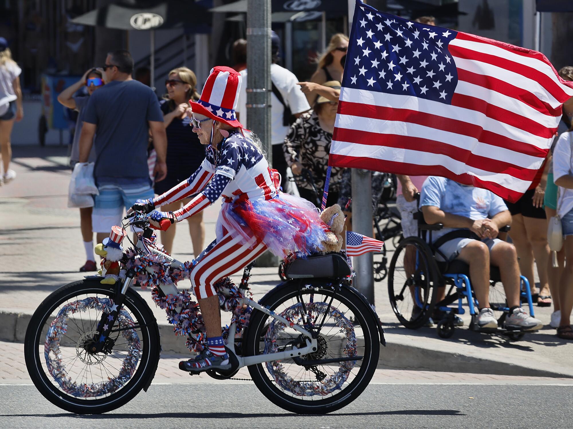 A person in red, white and blue rides a bike with a U.S. flag