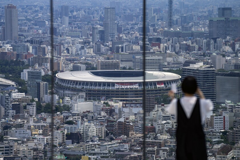 یک استادیوم بزرگ بیضی شکل با یک بنر Tokyo 2020 از یک عرشه رصد یک آسمان خراش دیده می شود