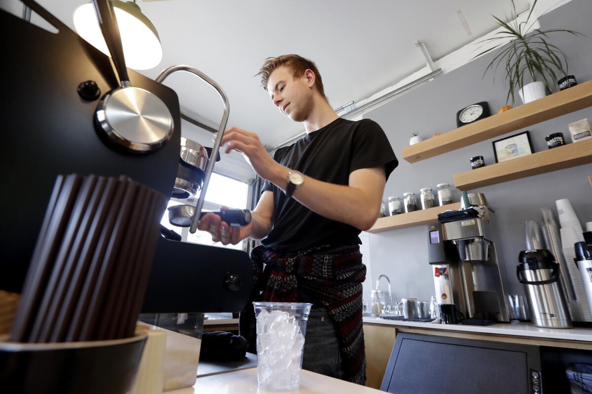 En esta imagen del 4 de noviembre de 2019, el barista Porter Hahn prepara un café helado para un cliente en una cafetería de Seattle. (AP Foto/Elaine Thompson, Archivo)