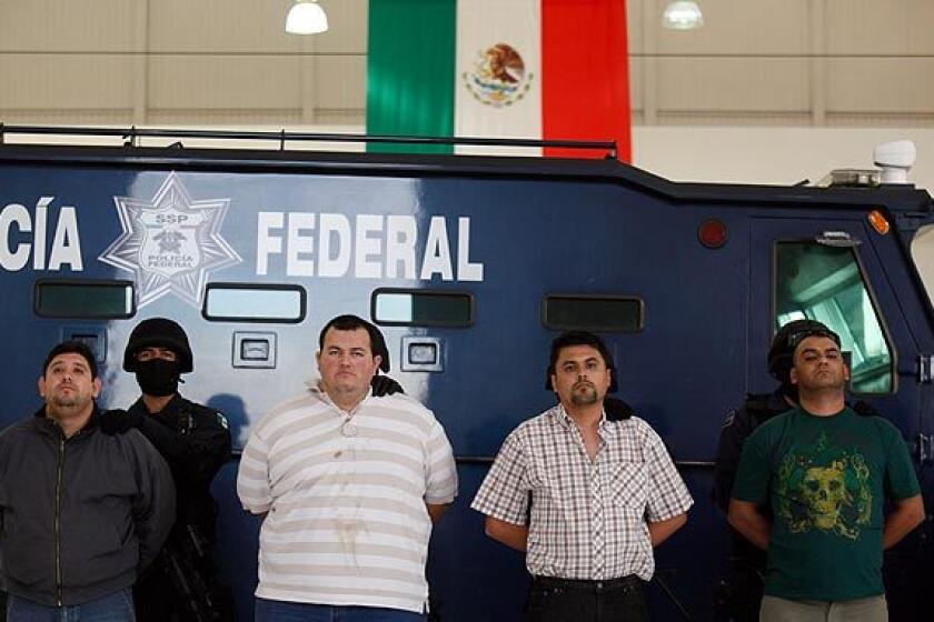 Alleged drug cartel members Jose Manuel Garcia Simental, center left, and Raydel "Crutches" Lopez Uriarte, center right, together with two unidentified men, are guarded by federal police as they are presented to the media in Mexico City.