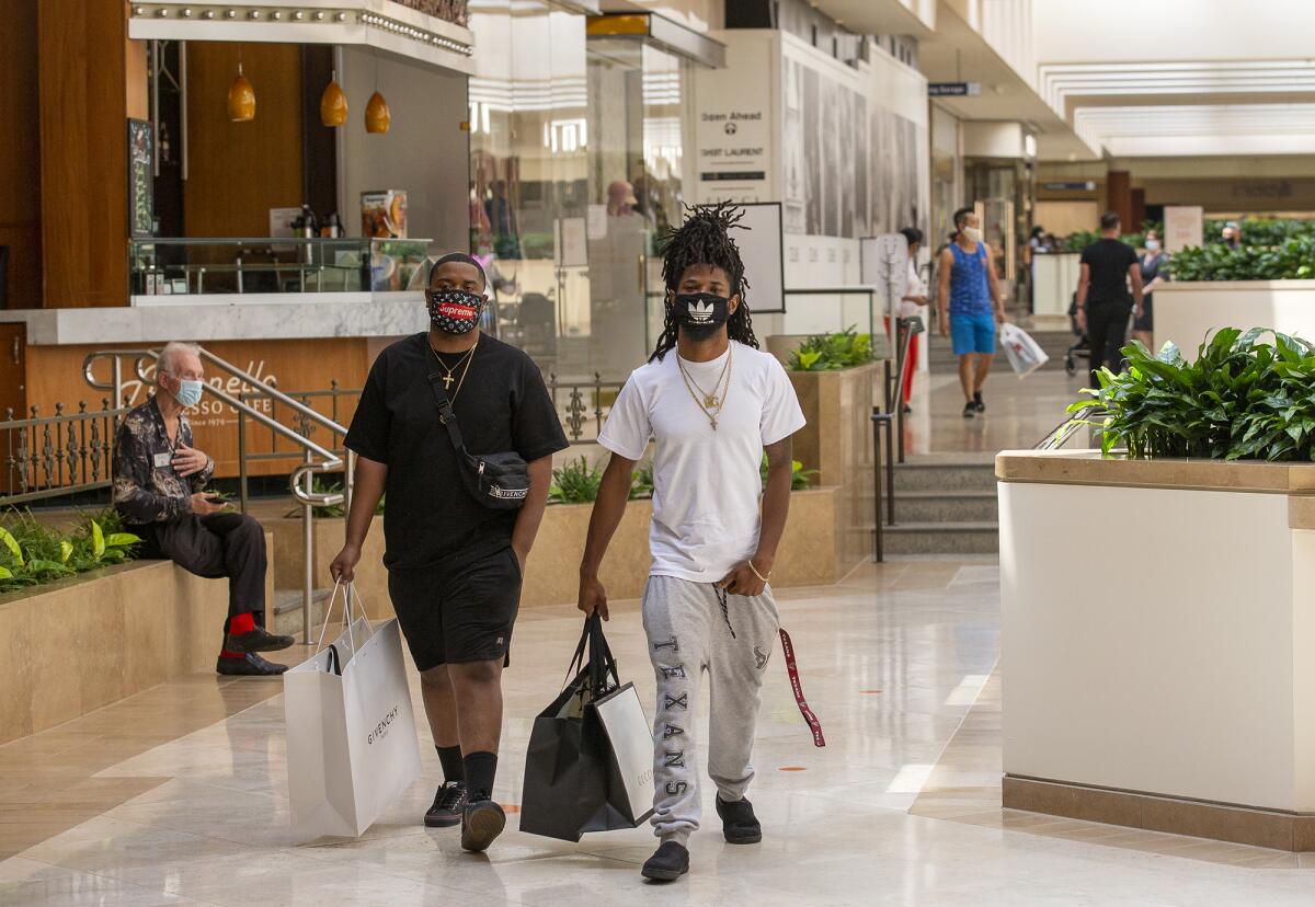 Jeff Luckey, left, and Tarique Lusk shop during the reopening of South Coast Plaza in Costa Mesa on Monday.