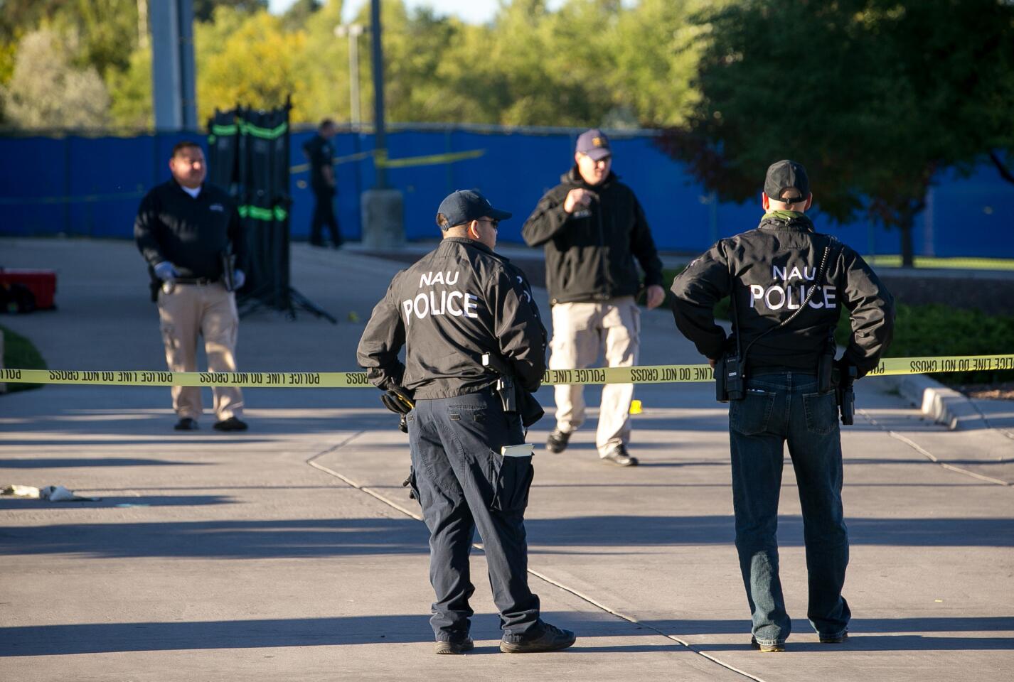 Police officers investigate a shooting at Northern Arizona University campus in Flagstaff, Ariz. An overnight confrontation between two groups of students escalated into gunfire early Friday when a student killed one person and wounded three others.