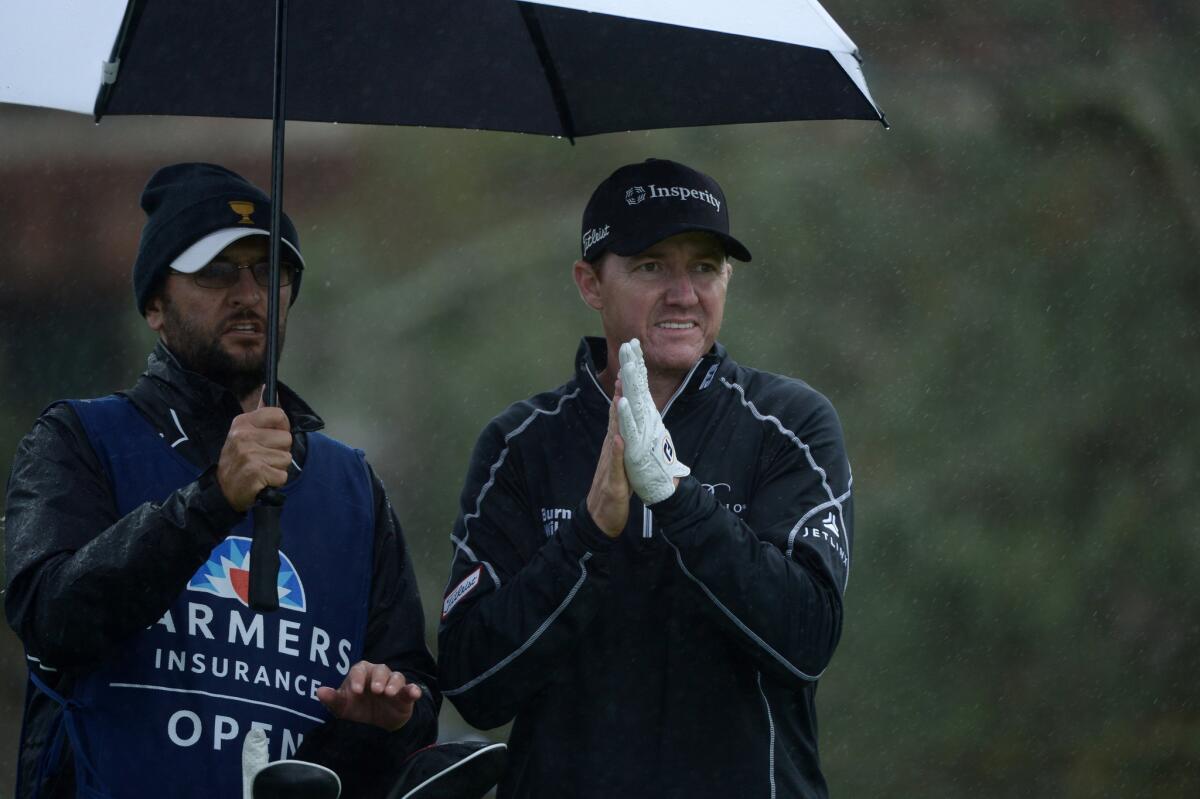 Jimmy Walker, right, stands under an umbrella on the 11th tee box during the final round of the Farmers Insurance Open at Torrey Pines.