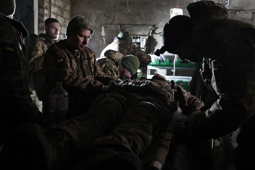 Ukrainian servicemen give the first aid to a soldier wounded in a battle with the Russian troops in their shelter in the Donetsk region, Ukraine, Thursday, Dec. 1, 2022. A top adviser to Ukraine's president has cited military chiefs as saying 10,000 to 13,000 Ukrainian soldiers have been killed in the country's nine-month struggle against Russia's invasion, a rare comment on such figures and far below estimates of Ukrainian casualties from Western leaders. Late Thursday, Dec. 1, 2022, Mykhailo Podolyak, a top adviser to Ukrainian President Volodymyr Zelenskyy, relayed new figures about Ukrainian soldiers killed in battle, while noting that the number of injured troops was higher and civilian casualty counts were “significant.” (AP Photo/Roman Chop)