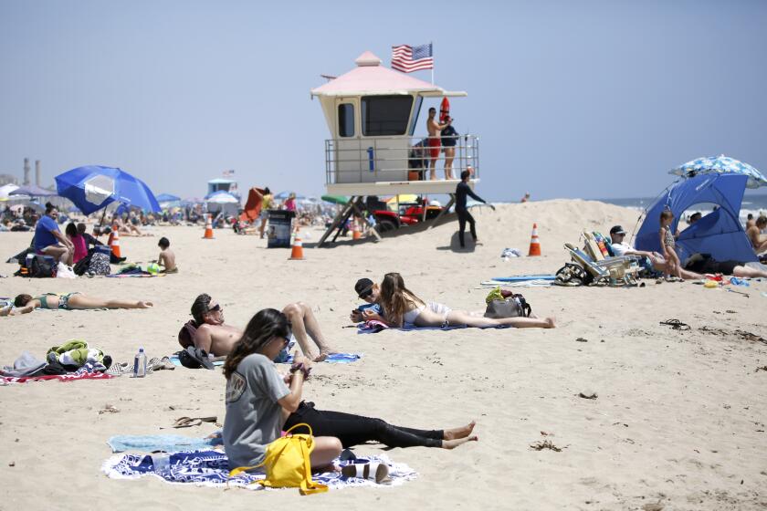 Beachgoers sunbathe near the Huntington Beach Pier on Saturday.