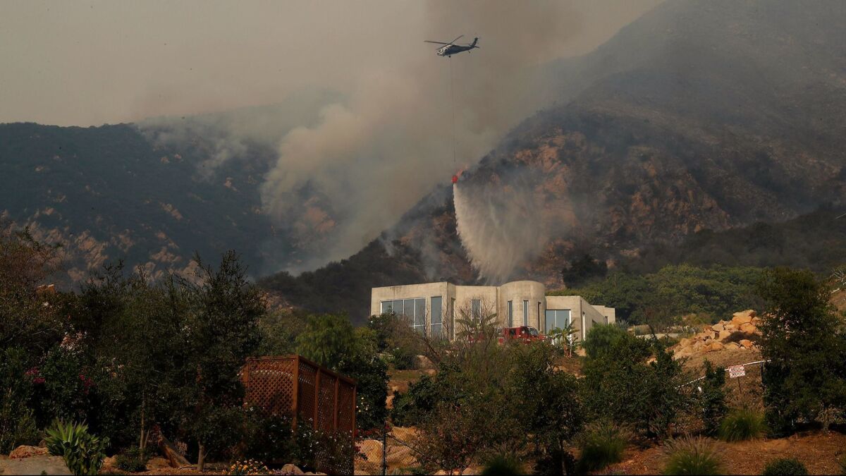A chopper dumps water on brush above a home on Toro Canyon Road in Montecito as the Thomas fire burns closer.