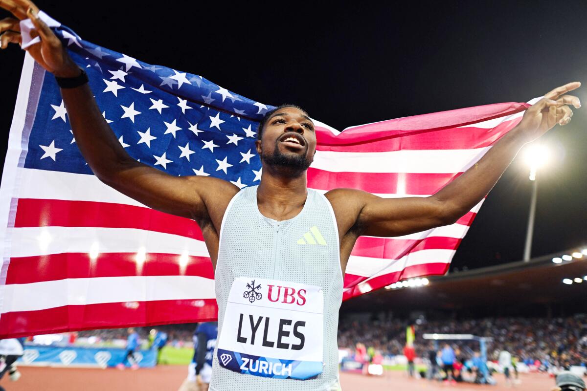 Noah Lyles is holding a U.S. flag as he celebrates after winning the 200 meters in Zurich, Switzerland.