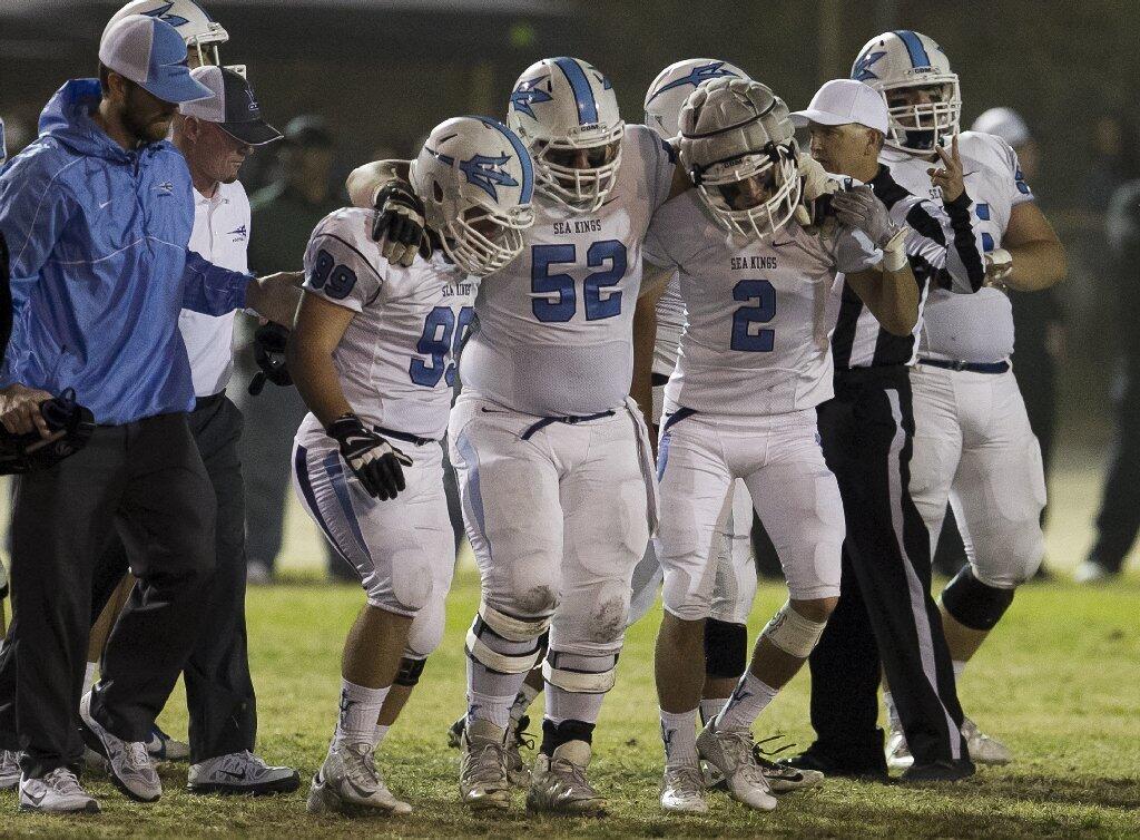 Corona del Mar High's Teddy Barber, left, and Sutty Barbato help Bryan Samudro off the field after an injury in the first half against Buena Park.