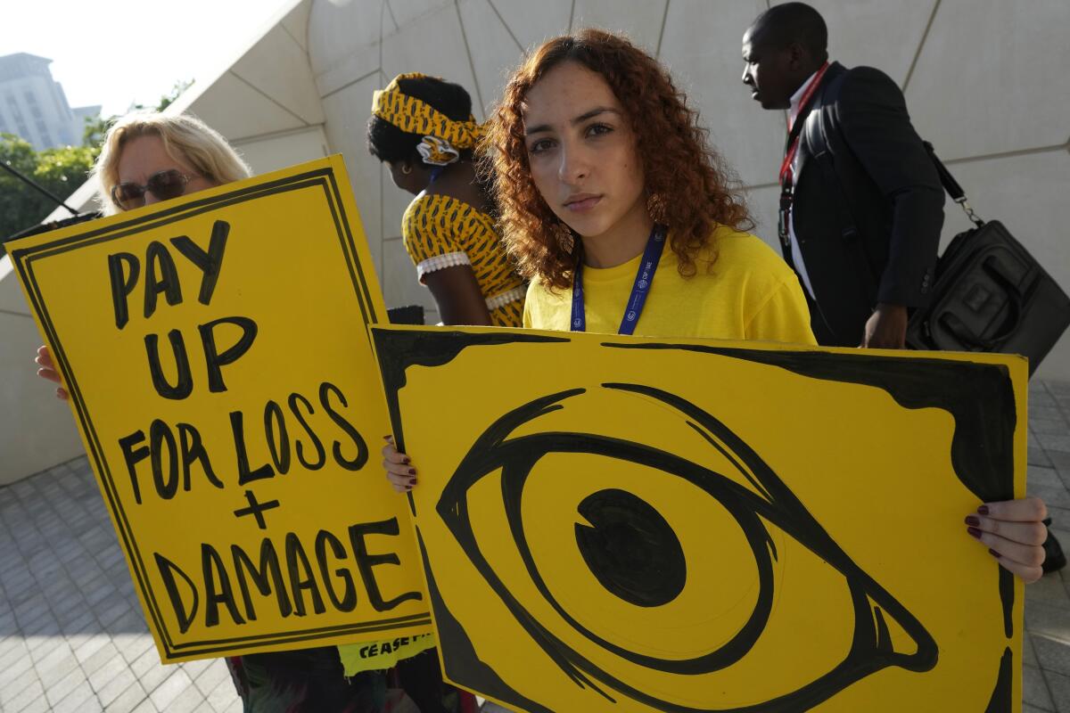 Una persona sostiene un cartel que reclama pagos por pérdidas y daños en la cumbre climática COP28, 