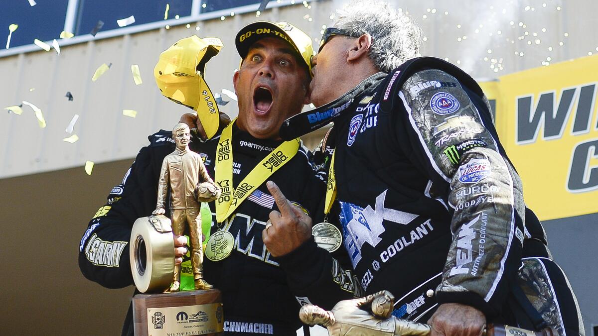Top fuel driver Tony Schumacher gets a smooch from funny car driver John Force during the awards ceremony at the NHRA Mile High Nationals at Bandimere Speedway on July 24, 2016.