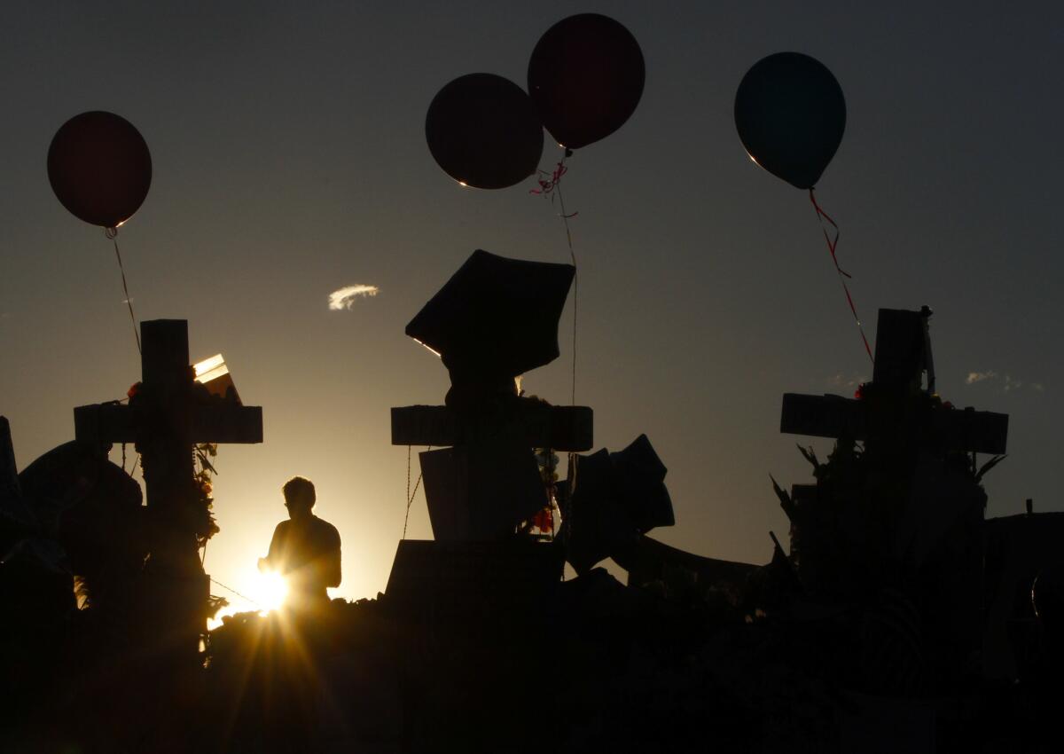 The sun rises behind a roadside memorial days after the July 2012 theater massacre in Aurora, Colo. More than three years later, the gunman has been sentenced to life in prison without the possibility of parole.