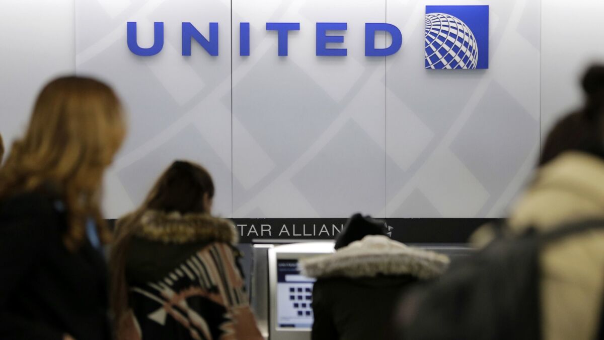 People stand in line at a United Airlines counter at LaGuardia Airport in New York. The airlines' brand has taken a beating after a dog stored in an overhead bin during a flight from Houston to New York died last week.