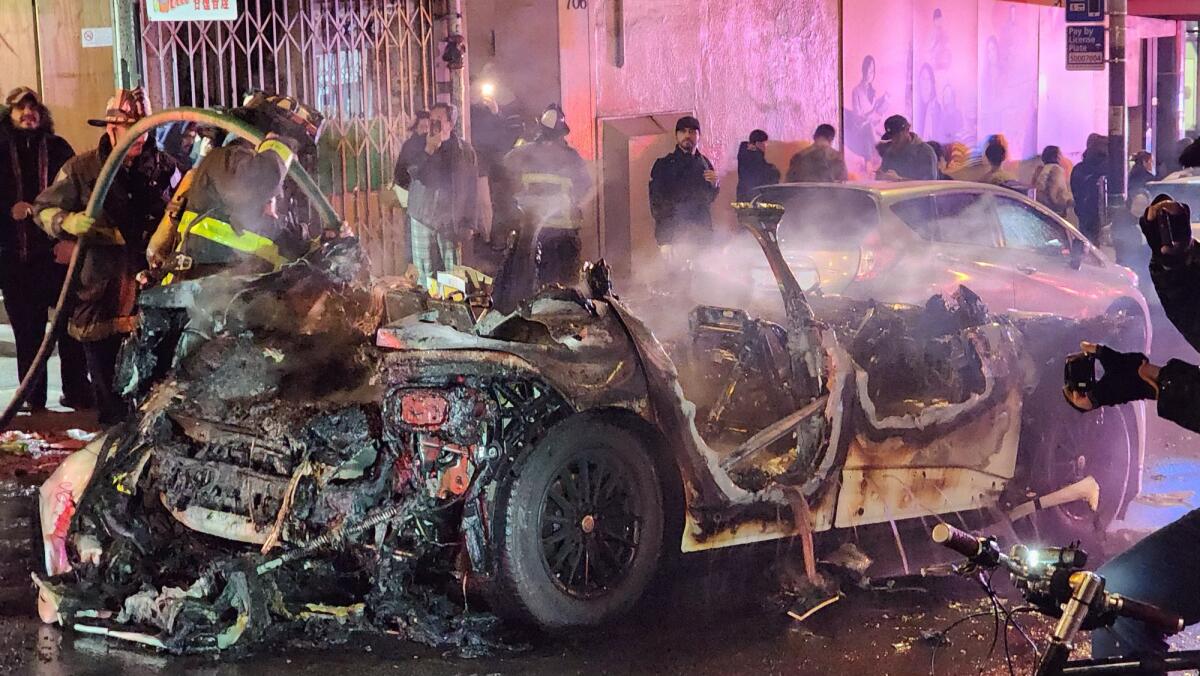 Firefighters surround a scorched driverless car.