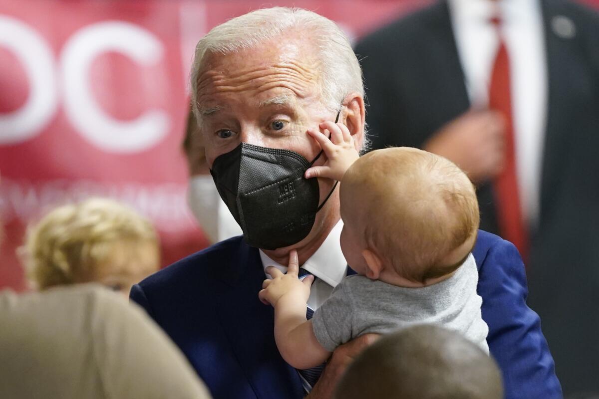 President Biden holds a baby who is touching Biden's face  