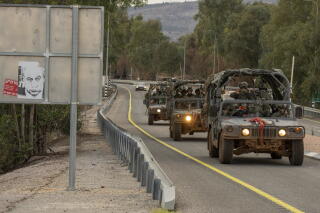 Israeli military vehicles pass a cartoon sign of Prime Minister Benjamin Netanyahu in northern Israel.