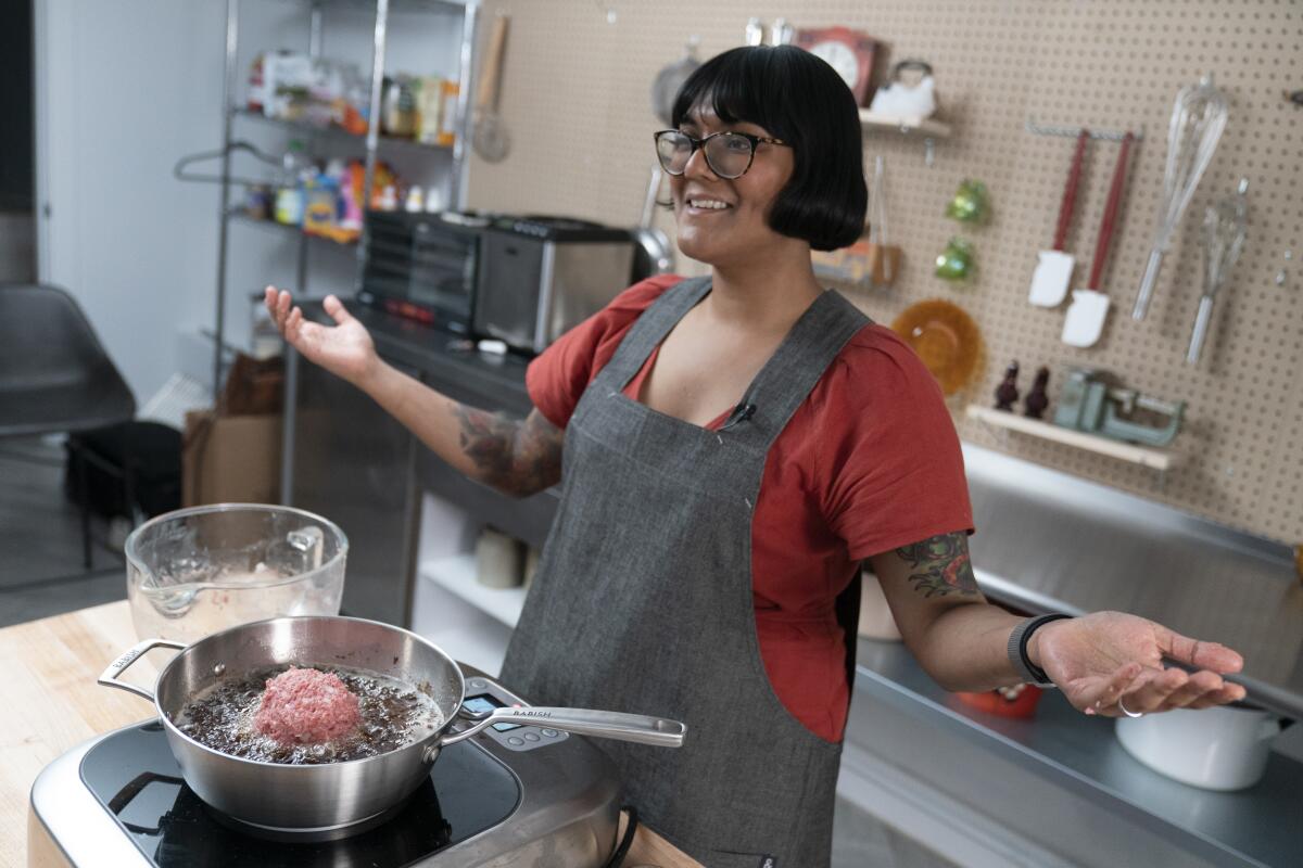 A woman stands behind a pan