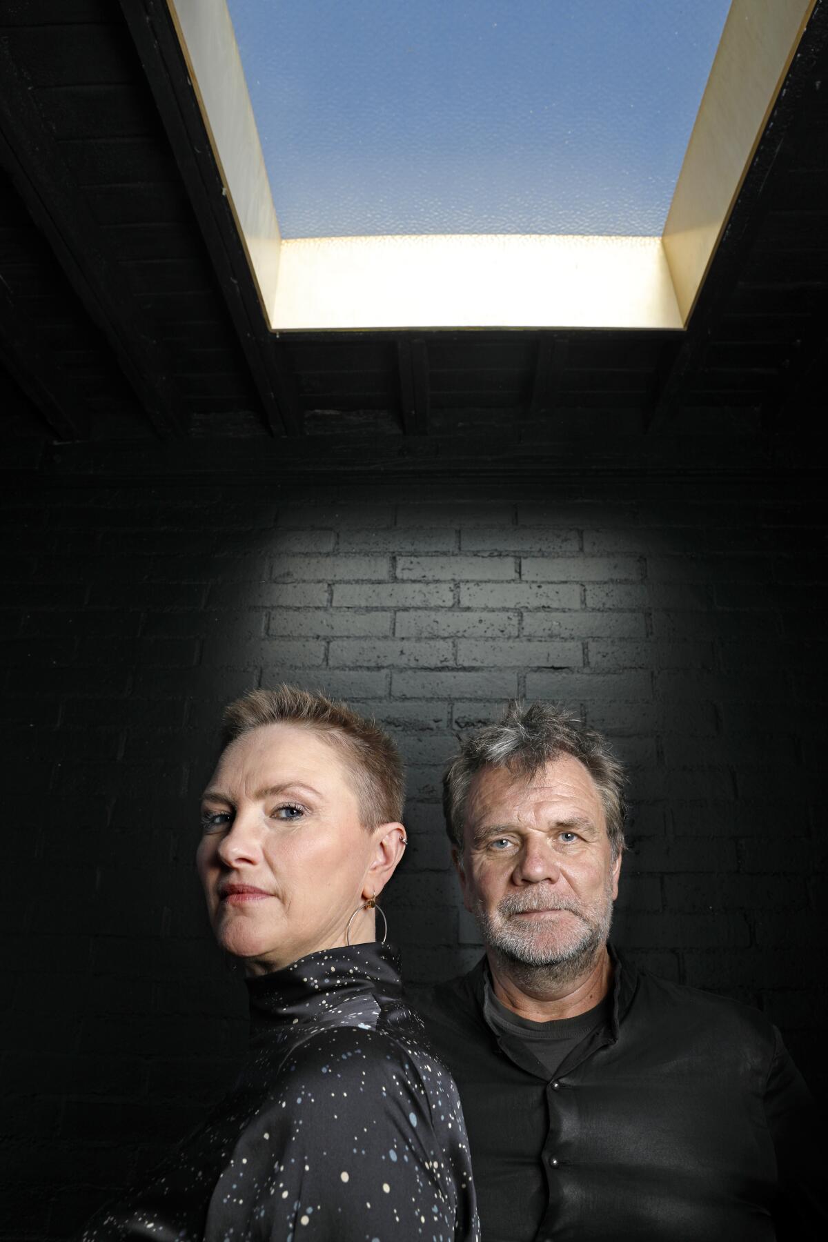 A woman and man stand together beneath a skylight.