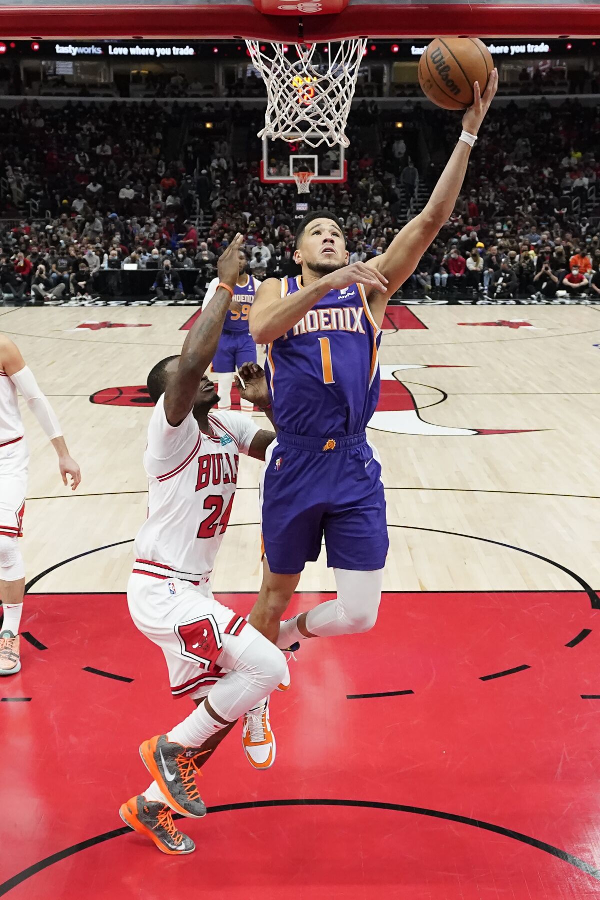 Phoenix Suns' Devin Booker (1) scores past Chicago Bulls' Javonte Green during the first half of an NBA basketball game Monday, Feb. 7, 2022, in Chicago. (AP Photo/Charles Rex Arbogast)
