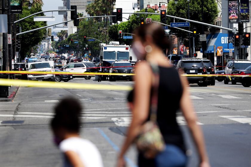 HOLLYWOOD, CALIFORNIA: Pedestrians are turned around at the intersection of Hollywood Boulevard and Highland Avenue while police investigate an officer involved shooting on Thursday, July 15, 2021. (Christina House / Los Angeles Times)