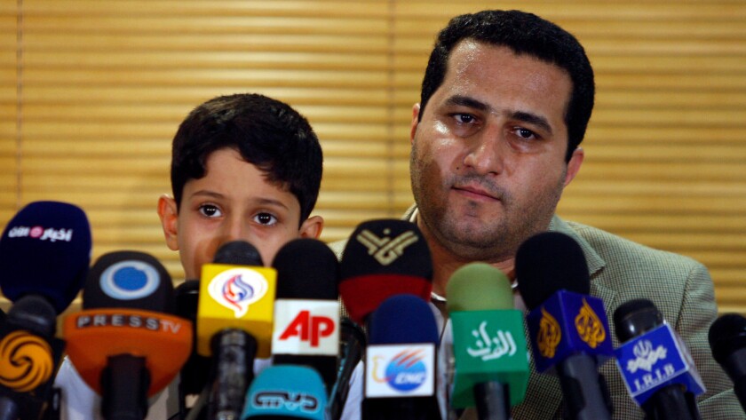Nuclear scientist Shahram Amiri attends a news briefing at the Imam Khomeini airport outside Tehran in July 2010. He's holding his son, Amir Hossein.