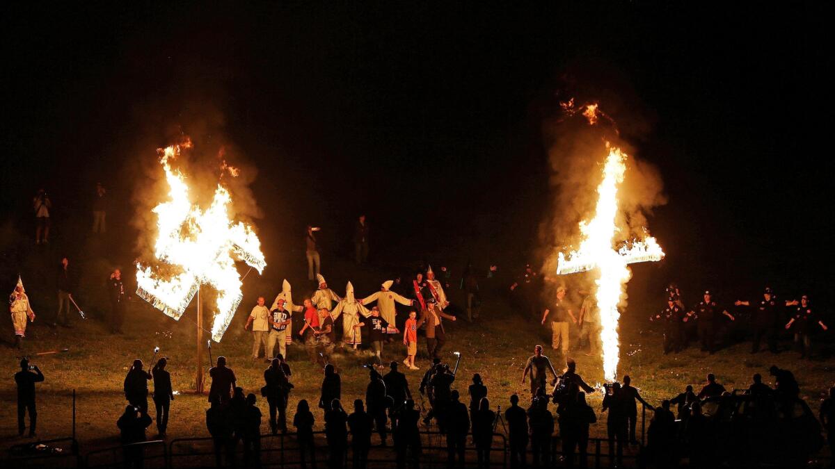 In this April 23, 2016, photo, members of the Ku Klux Klan participate in cross and swastika burnings after a "white pride" rally in rural Paulding County near Cedar Town, Ga.
