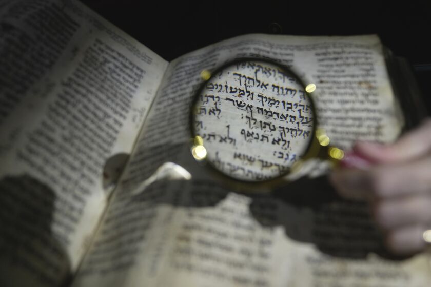 A member of staff shows the Hebrew Bible "Codex Sassoon", that dates back more than 1,000 years, on display during a media preview of Sotheby's auction, in London, Wednesday, Feb. 22, 2023. The piece has an estimated price of US$30-50 million and will go on auction on May in New York. (AP Photo/Kin Cheung)