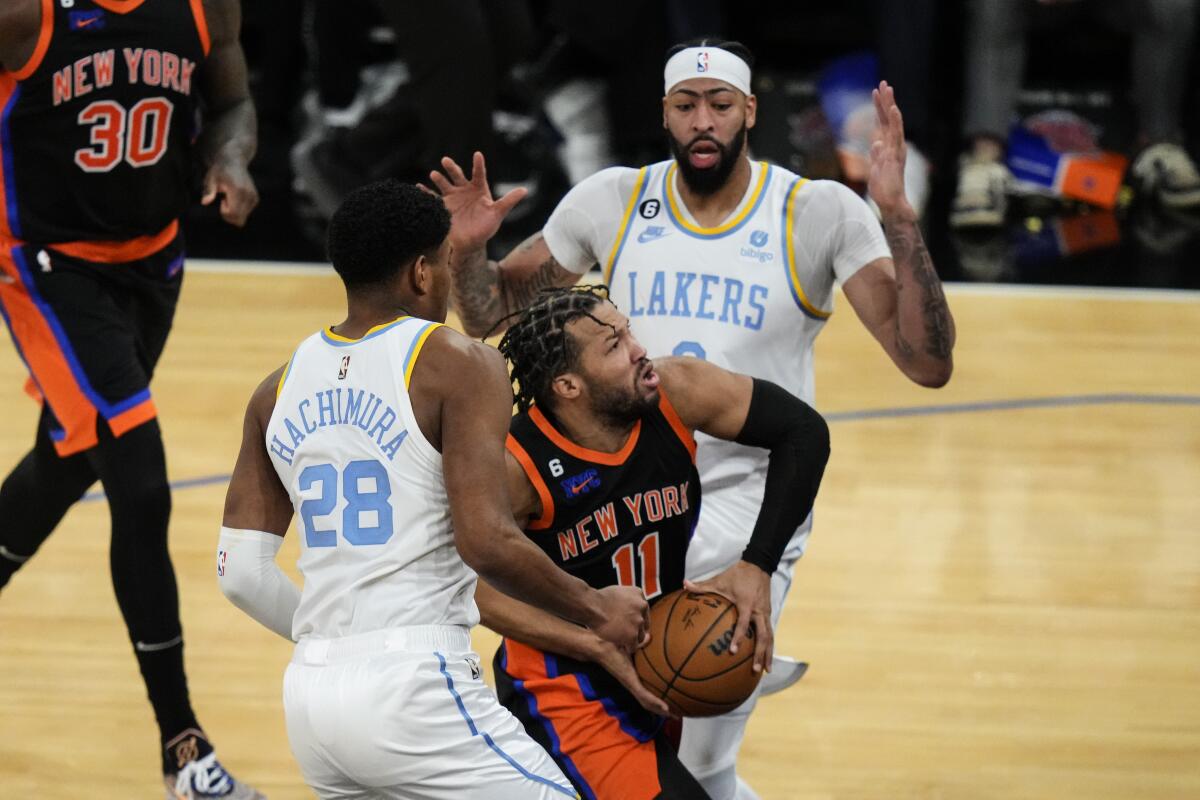 Lakers' Rui Hachimura and Anthony Davis defend New York Knicks' Jalen Brunso during overtime.