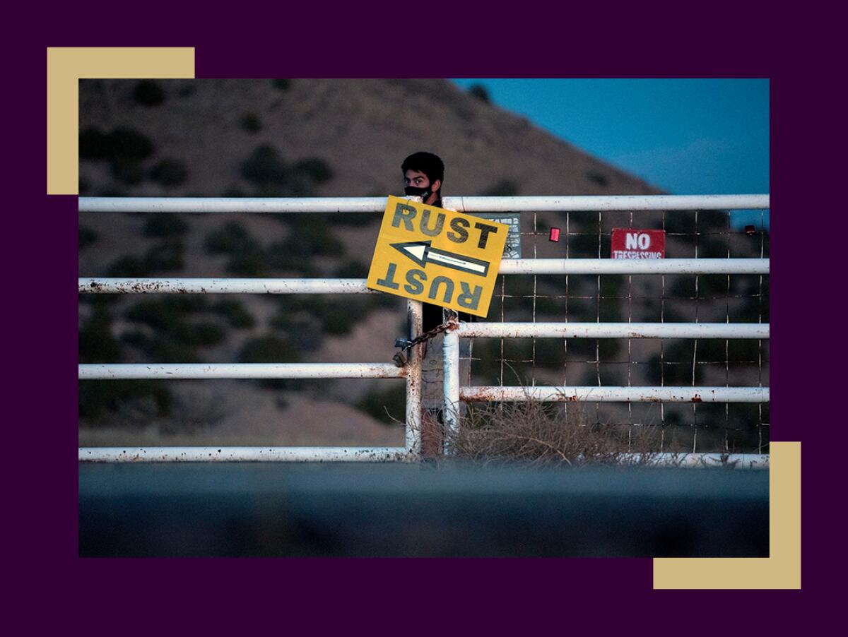 A person stands behind a closed gate with a sign pointing to the "Rust" set.