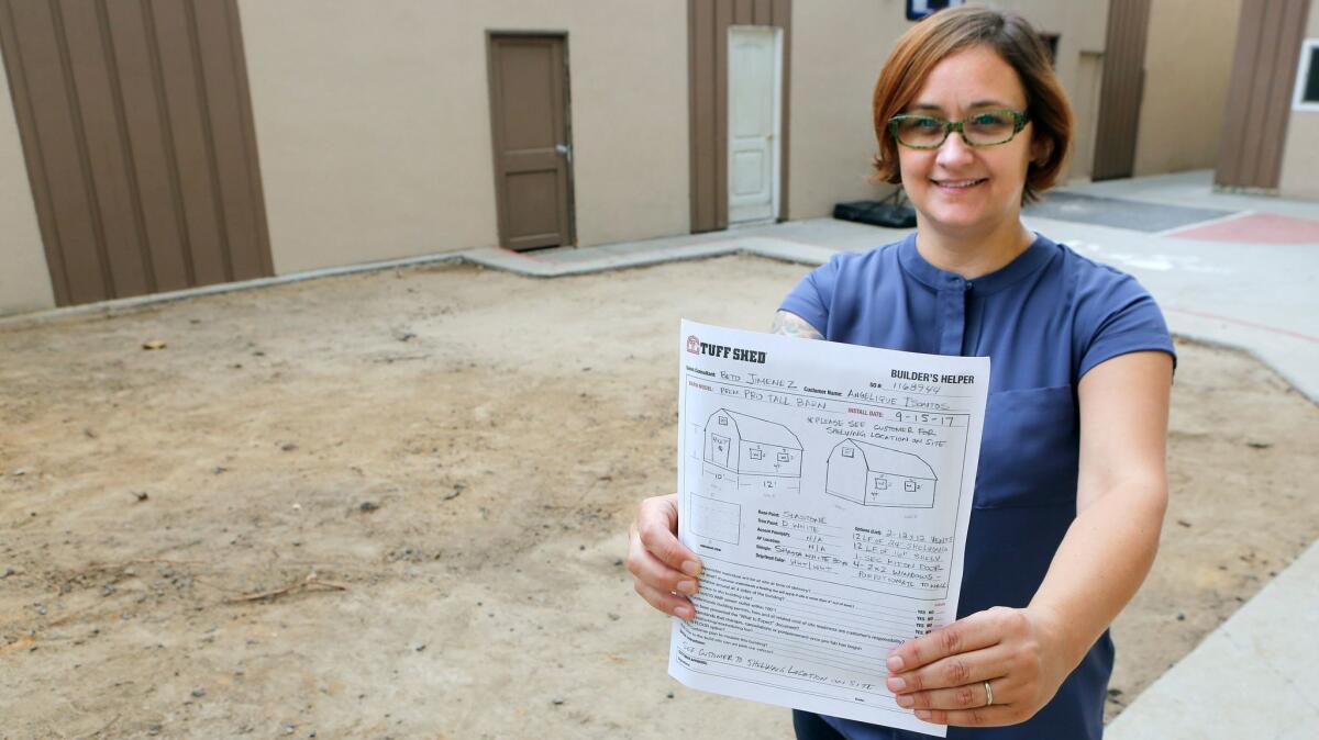 Women's Transitional Living Center CEO Gigi Tsontos holds plans for a 12-foot by 10-foot shed for pets that will occupy this empty area of the property.