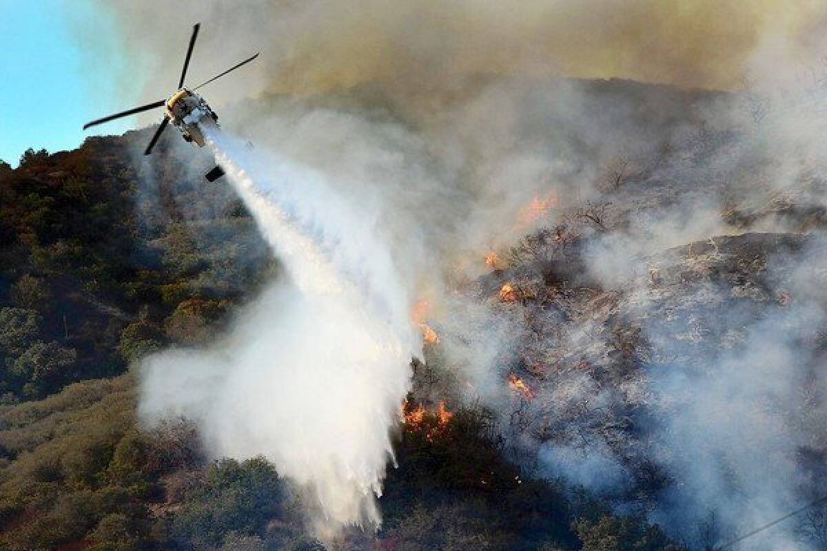 An L.A. County helicopter drops water in a battle against a rapidly moving brush fire in the Sepulveda Pass.