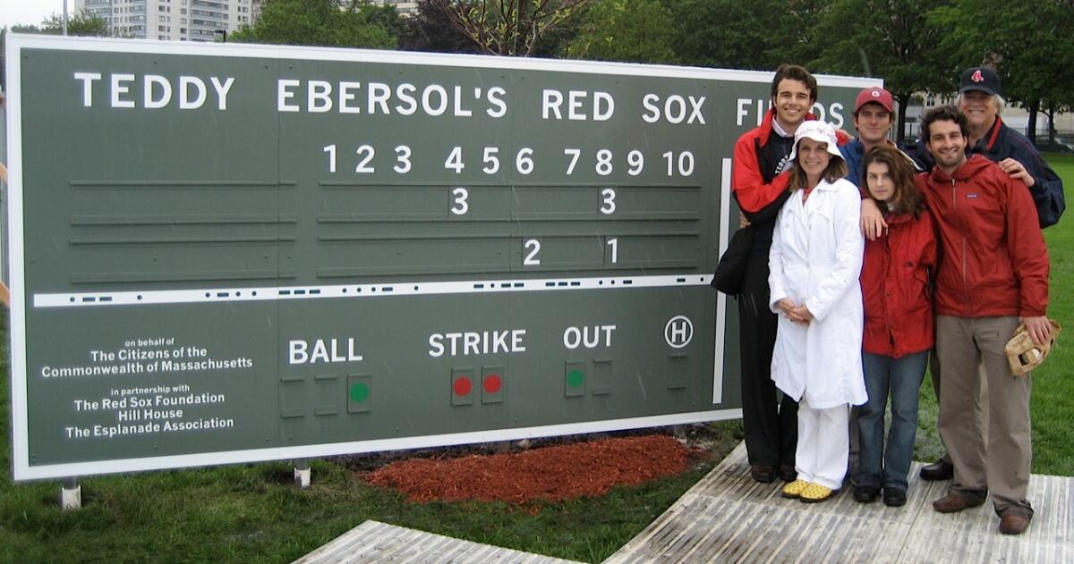 The Ebersol family stands near the scoreboard, that replicates the one on the "Green Monster" at Fenway Park.