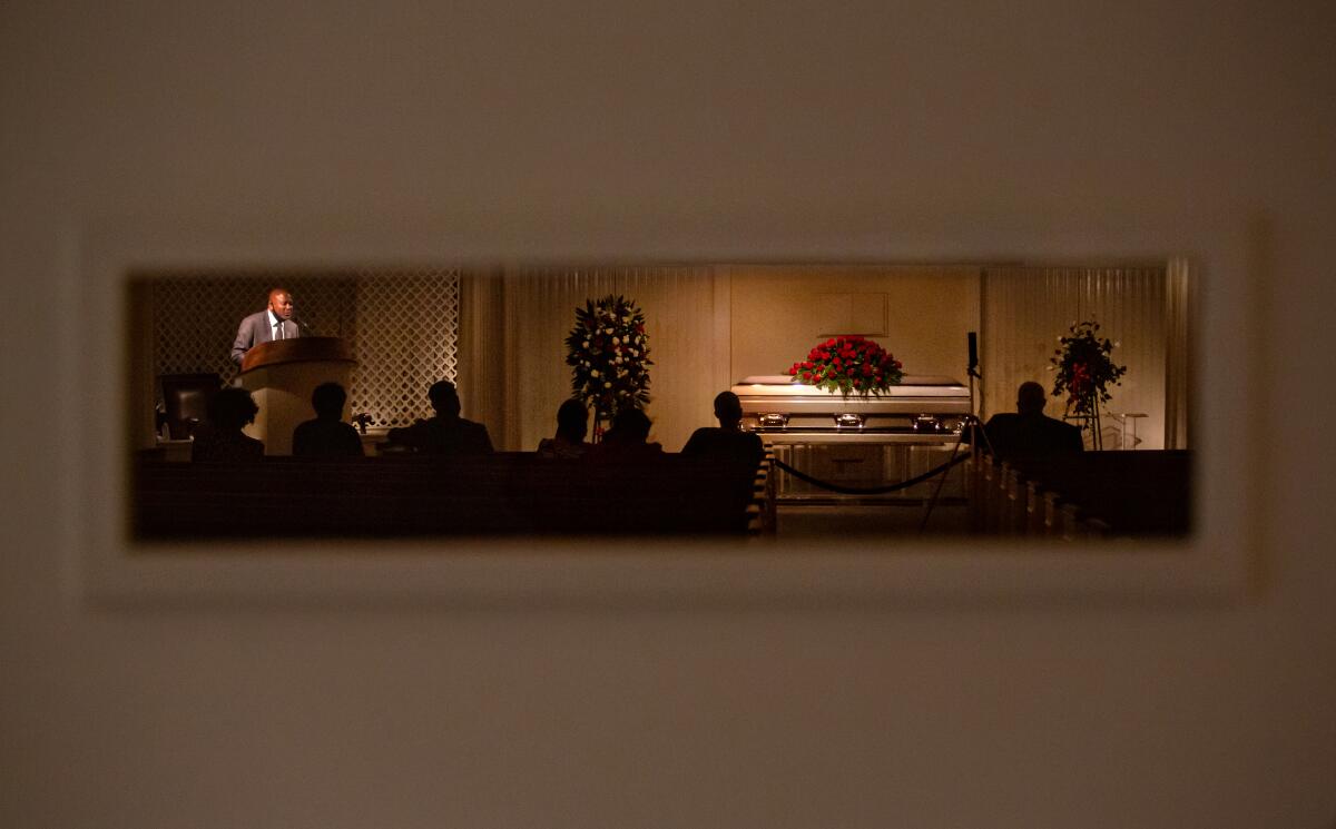 The funeral of Charles Jackson Jr., who died of COVID-19, is seen through a window.