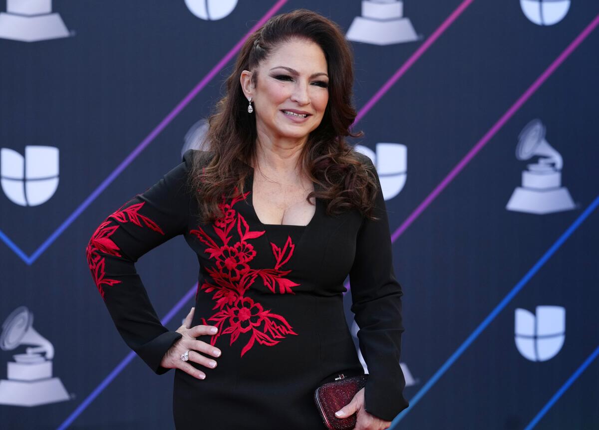 A woman with long hair posing in a black dress with red accents