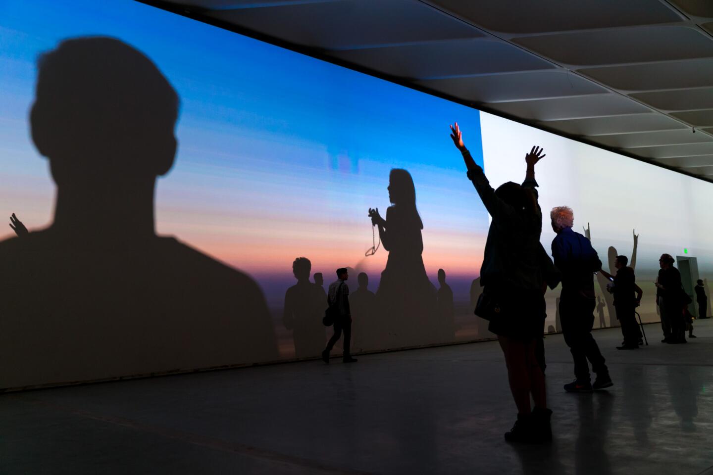 Visitors play with shadows during the light projections of "Stillness," an art installation by Yann Novak, in the expansive third floor gallery, during a public sneak peek event at the Broad Museum.