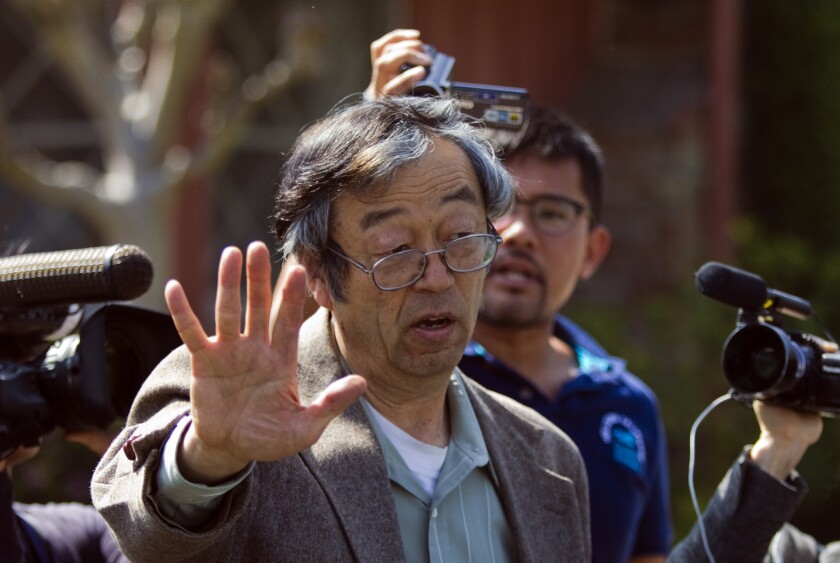 Journalists surround Dorian Satoshi Nakamoto, believed to be the creator of Bitcoin, as he walks from his home to a car in Temple City.