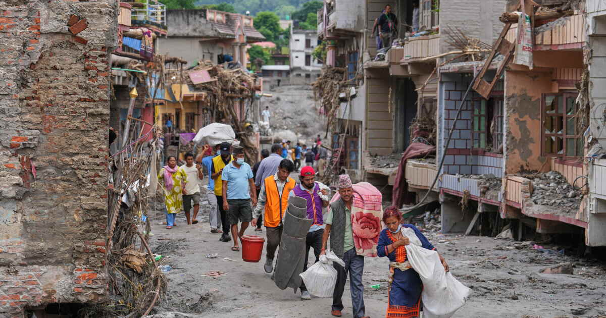 Photo: latimes.com Residents carry their belongings salvaged from their damaged homes filled with mud and debris in Devighat, in Nepal's
