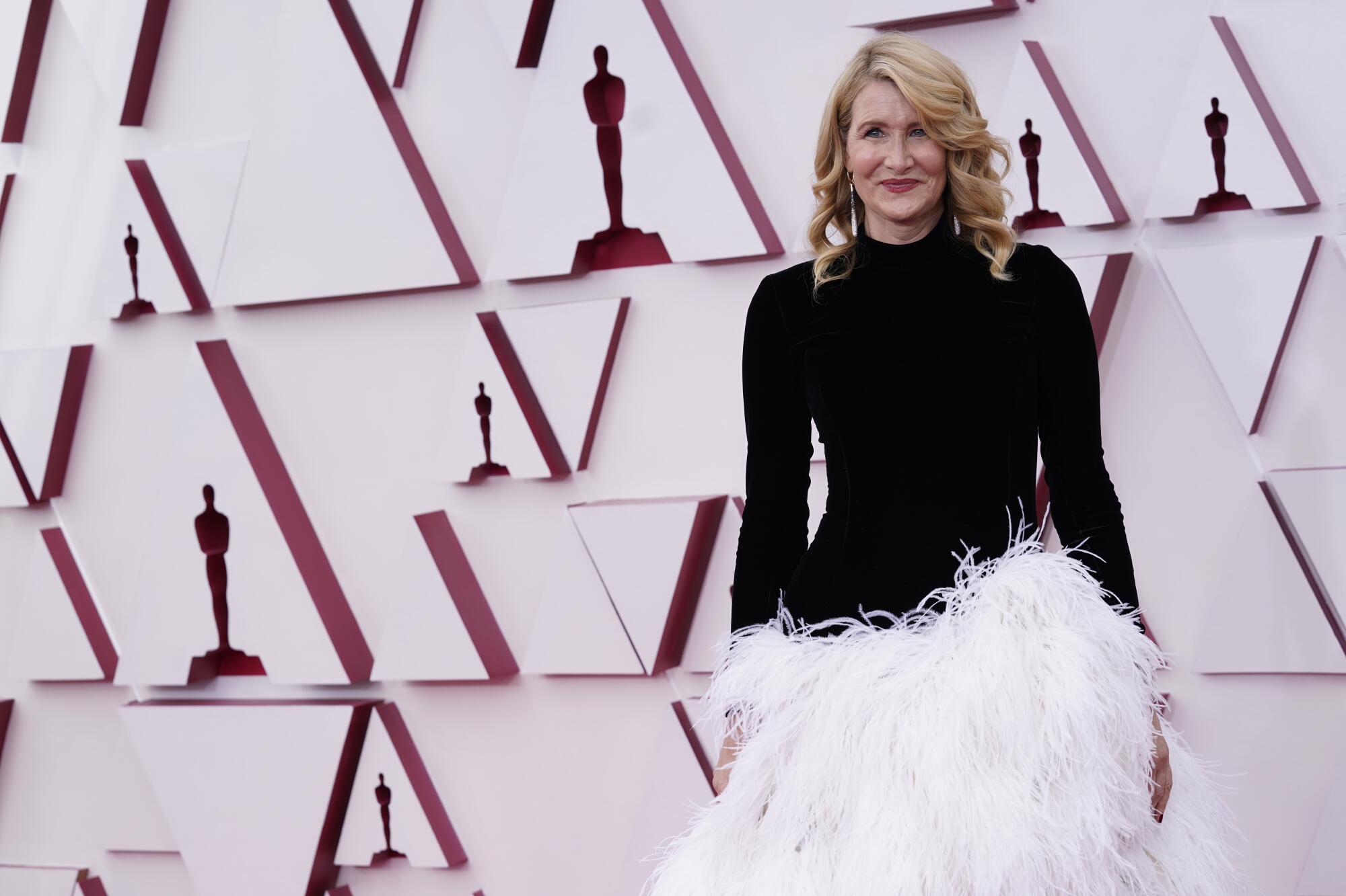 Laura Dern wears a dress with a black turtleneck top and white feathery skirt