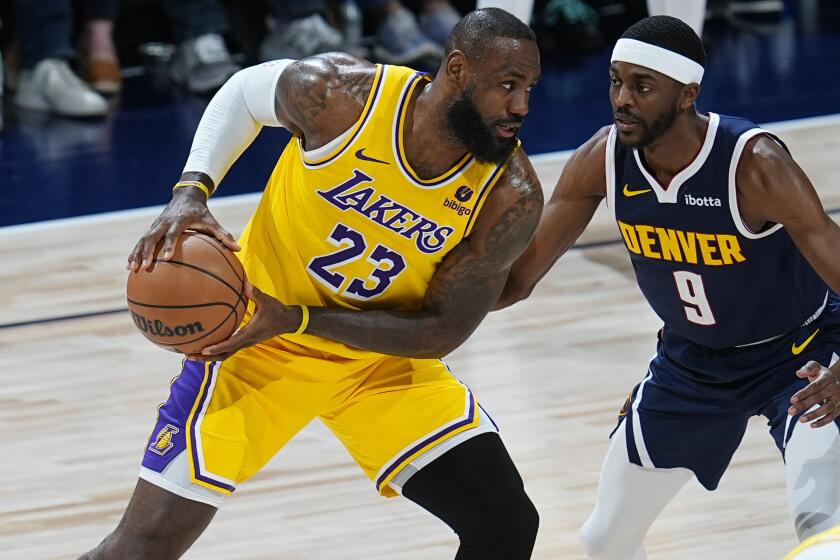 Los Angeles Lakers forward LeBron James, left, looks to pass the ball as Denver Nuggets forward Justin Holiday, right, defends in the first half of Game 5 of an NBA basketball first-round playoff series Monday, April 29, 2024, in Denver. (AP Photo/David Zalubowski)