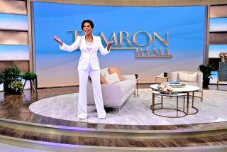 Tamron Hall, in white pantsuit, on the set of her ABC show