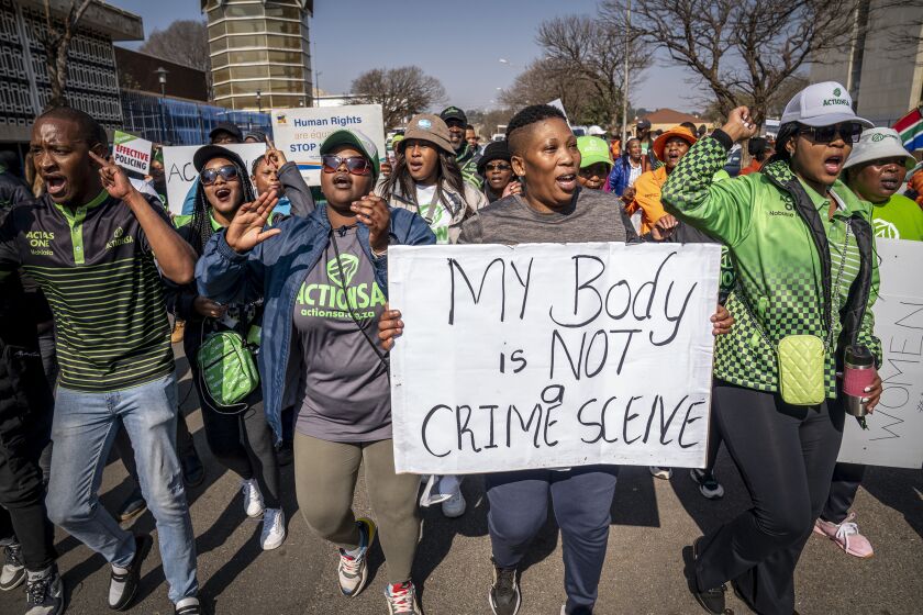 Women protest outside the Krugersdorp, South Africa, Magistrates Court Monday, Aug. 1, 2022. More than 80 men suspected of the gang rapes of eight women and armed robbery of a video production crew in the ming town, west of Johannesburg appeared in court on Monday. (AP Photo/Shiraaz Mohamed)