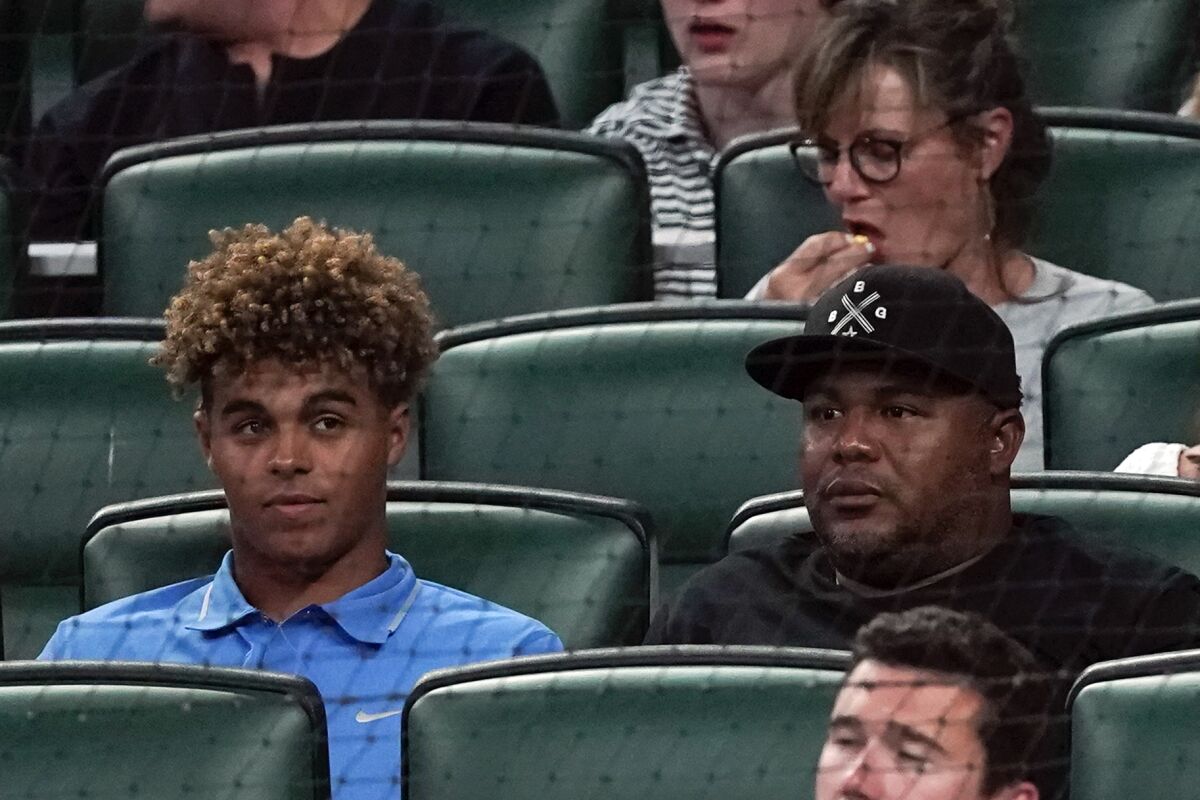 Former Atlanta Braves outfielder Andruw Jones, right, sits with his son, Druw, at a game.