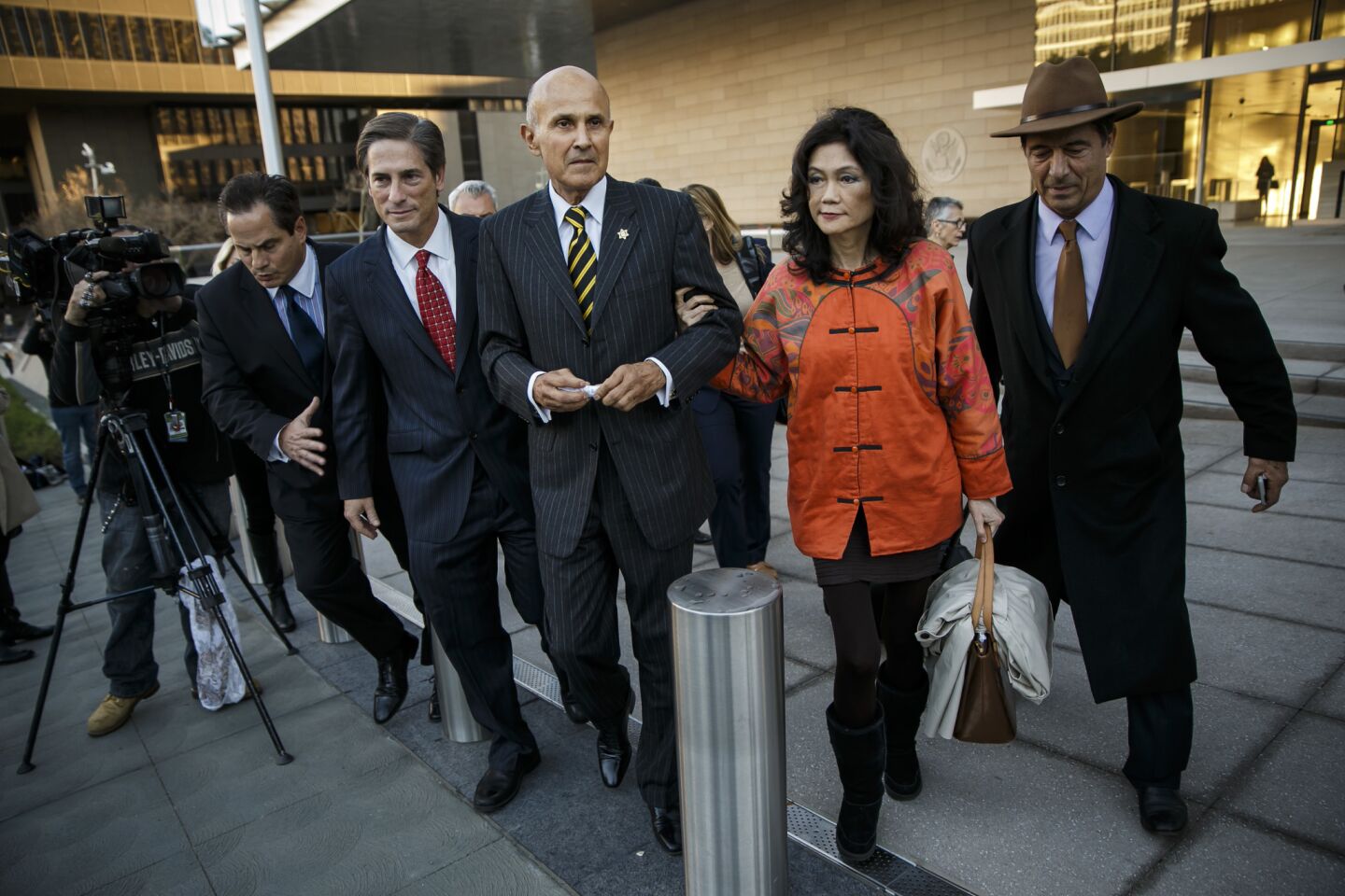 Former Los Angeles County Sheriff Lee Baca, center, escorted by his wife, Carol Chiang, right, and h