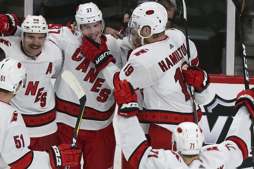 FILE - In this Nov. 16, 2019, file photo, Carolina Hurricanes' Dougie Hamilton (19) grabs the chin of teammate Andrei Svechnikov (37), of Russia, while the rest of the team joins to celebrate Svechnikov's winning goal against the Minnesota Wild during overtime of an NHL hockey game. The Hurricanes are determined to make a second straight deep run in the Stanley Cup playoffs. That can only happen if they do something they have rarely done over the past decade: defeat the New York Rangers. (AP Photo/Stacy Bengs)