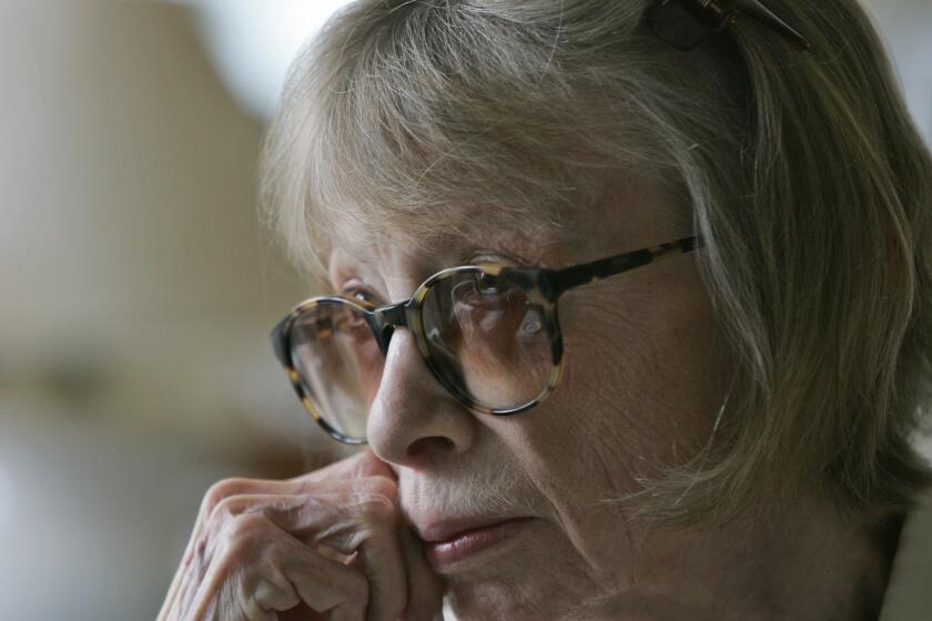 A close-up of Joan Didion shows the author wearing glasses, leaning her chin into her hand